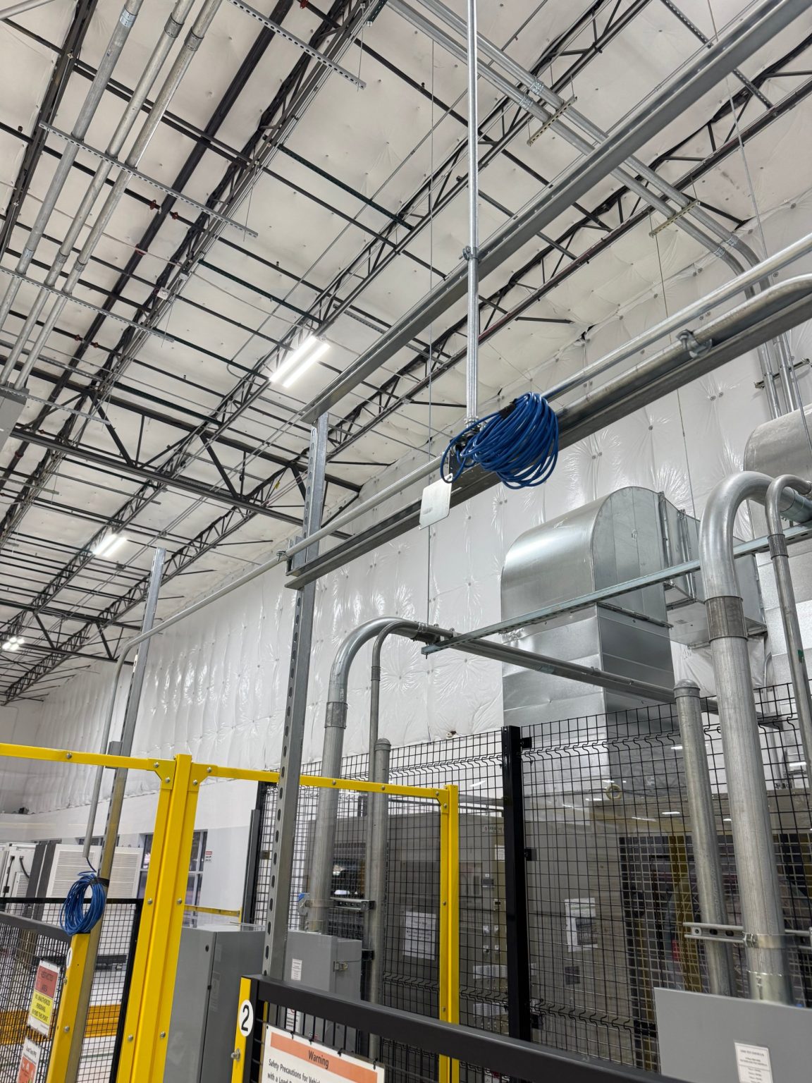 Conduit and cabling above EV charger test cells with safety fencing