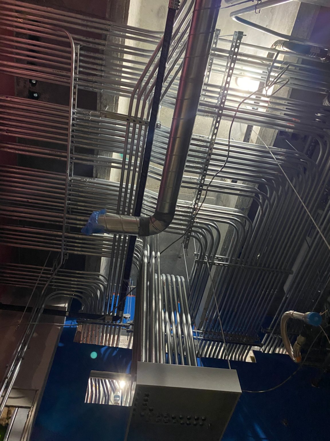 Rigid conduit runs on strut overhead in an industrial plant